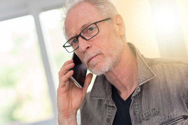 Portrait of mature man talking on phone, light effect - Photo, Image