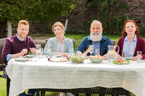 famiglia sorridente durante la cena in campagna
 - Foto, immagini