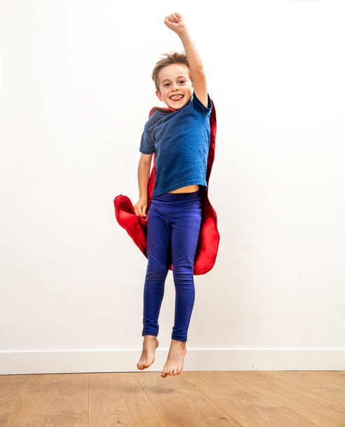 Laughing super hero boy jumping, reaching happiness and victory, indoor - Photo, Image