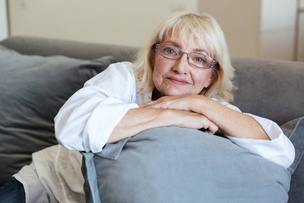 Sonriente señora madura sentada en un sofá
 - Foto, Imagen