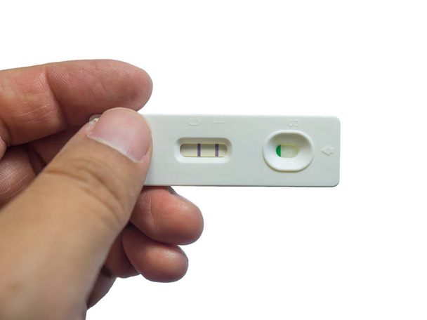 Ο άνθρωπος κρατώντας το θετικό τεστ εγκυμοσύνης στο χέρι απομονώνονται σε λευκό φόντο. - Φωτογραφία, εικόνα