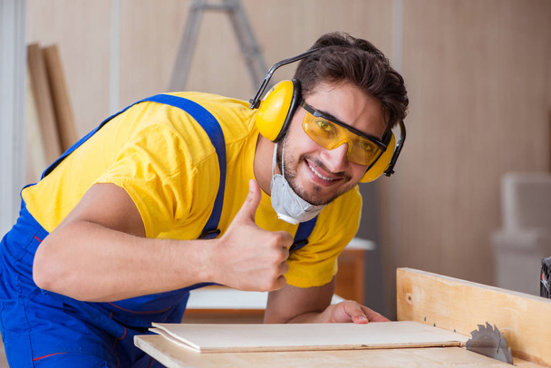 jovem carpinteiro reparador trabalhando corte de madeira em serra circular - Foto, Imagem