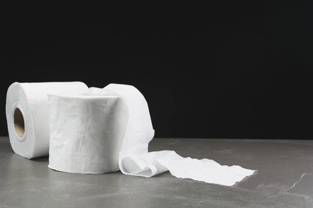 Close-up beeld van toilet papieren rollen op de tafel met donkere achtergrond. - Foto, afbeelding
