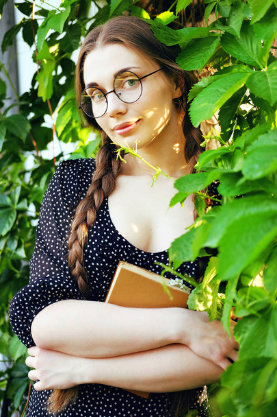 Young student woman with  long braids and a romance novel - Foto, afbeelding