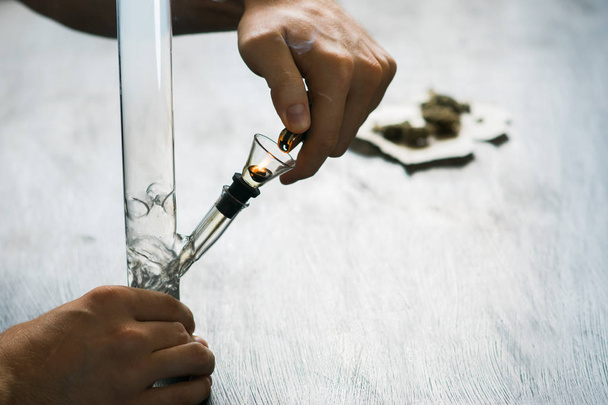man smokes using Bong and medical marijuana, cannabis thc flower Sativa and Indica Close up on a black background. lifestyle Concepts the legalization of marijuana in the world and the United States. - Photo, Image