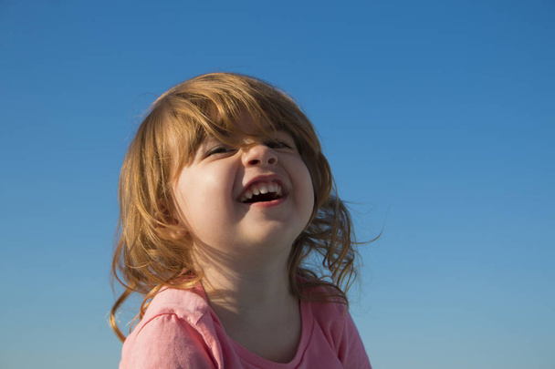 lachen meisje op een achtergrond van de hemel - Foto, afbeelding