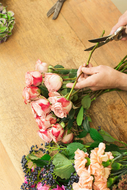 Άνθρωπος βοηθός στο κατάστημα παράδοση λουλουδιών βεβαιωθείτε closeup ροδαλή ανθοδέσμη - Φωτογραφία, εικόνα