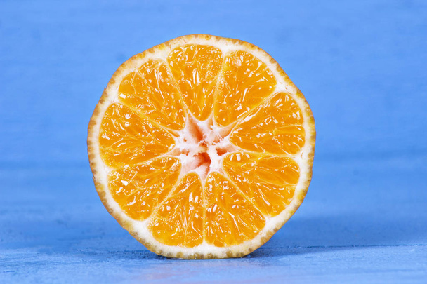 Fresh half cut oranges on blue wooden table. - Zdjęcie, obraz
