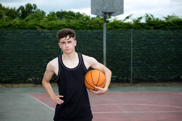 Teenage boy holding a basketball on a court - Fotoğraf, Görsel