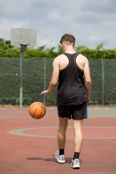 Teenage boy bouncing a basketball on a court - Zdjęcie, obraz