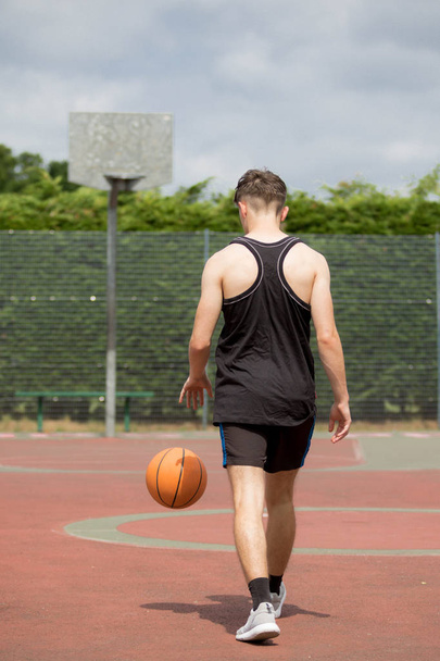 Teenage boy bouncing a basketball on a court - Foto, Imagem