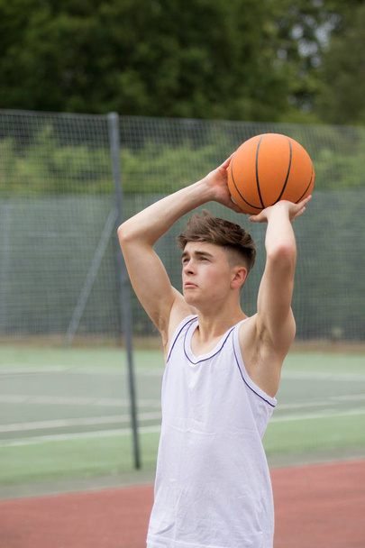 Teenage boy shooting a hoop on a basketball court - Photo, image