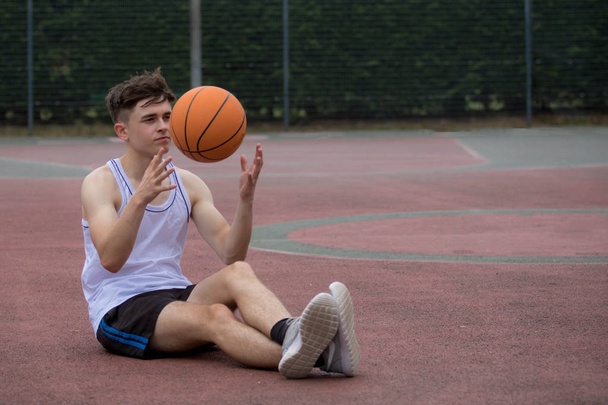 Teenage boy tossing a basketball from one hand to another on a c - Photo, Image