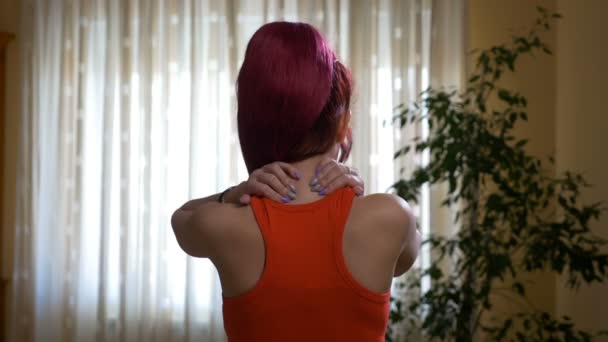Young woman having neck pain grabbing her back head - Materiał filmowy, wideo