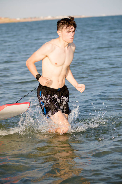 Teenage boy with a body board in the sea - 写真・画像