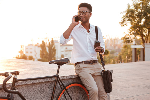 Attractive young african man morning with bicycle talking by phone. - Foto, immagini