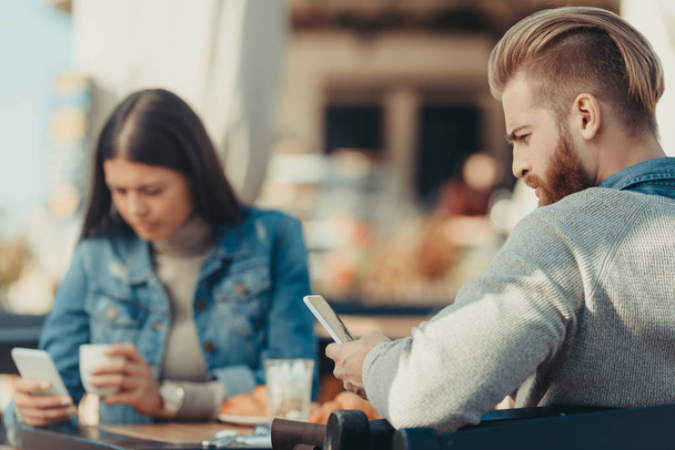 ζευγάρι ψάχνει στο smartphone στην καφετέρια - Φωτογραφία, εικόνα