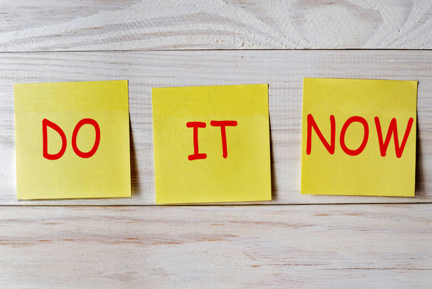 Do it now written on sticky note on wooden background - Photo, Image