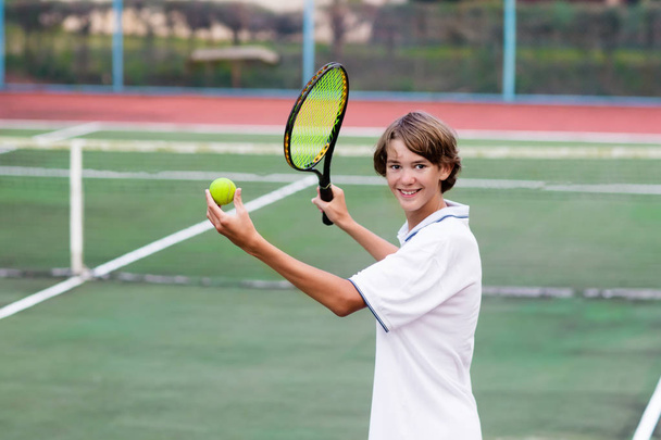 Lapsi pelaa tennistä ulkona kentällä
 - Valokuva, kuva