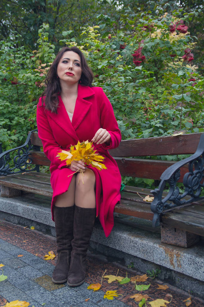 Mujer de abrigo rojo en el banco en el parque de otoño. Gente
 - Foto, imagen