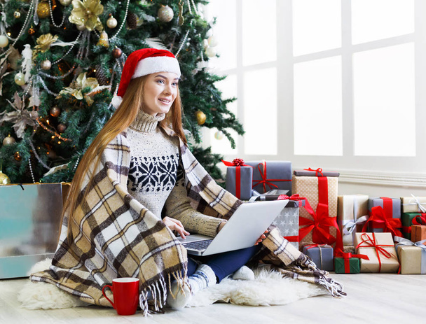 Young woman online on laptop at christmas interior - Foto, imagen