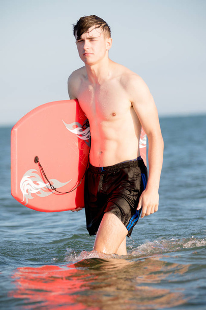 Teenage boy with a body board in the sea - Фото, зображення