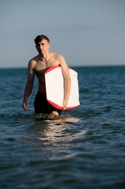 Teenage boy with a body board in the sea - Valokuva, kuva