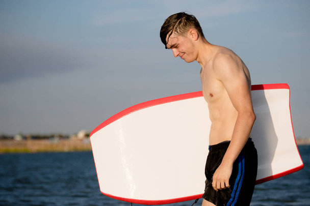 Teenage boy with a body board in the sea - Fotoğraf, Görsel