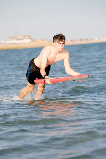 Teenage boy with a body board in the sea - 写真・画像
