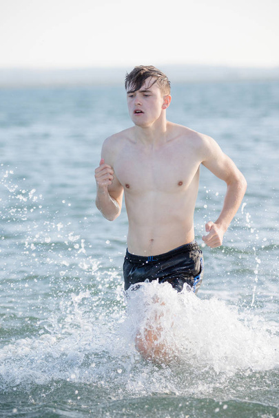 Teenage boy in the sea on a summer's day - Фото, зображення