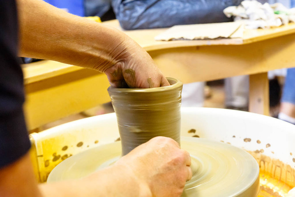 A pottery. Master on the circle makes a vase of clay. - Foto, imagen