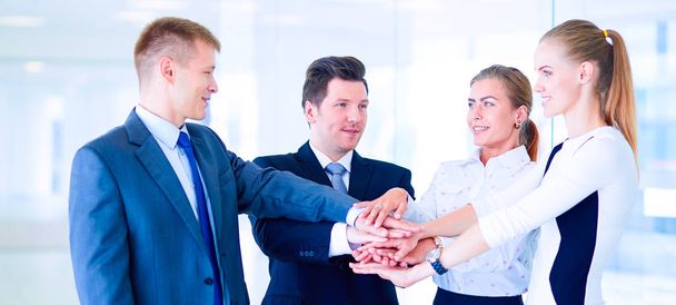 Business team joining hands together standing in office - Foto, imagen