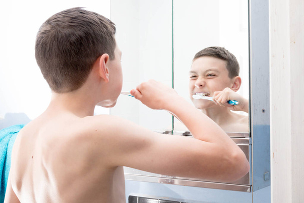 Young caucasian teenage boy brushing his teeth - 写真・画像