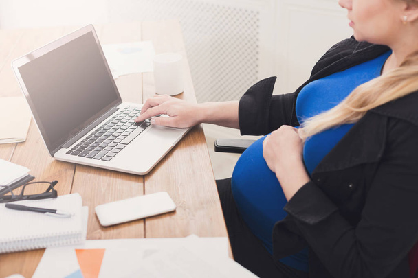 Беременная женщина работает на ноутбуке с пустым экраном
 - Фото, изображение