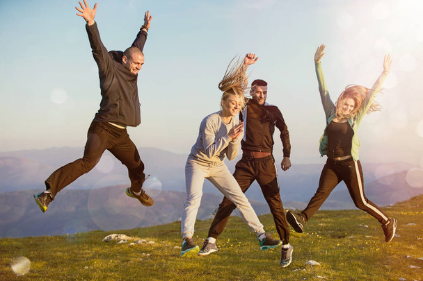 Group of friends running happily together in the grass and jumping - Fotoğraf, Görsel