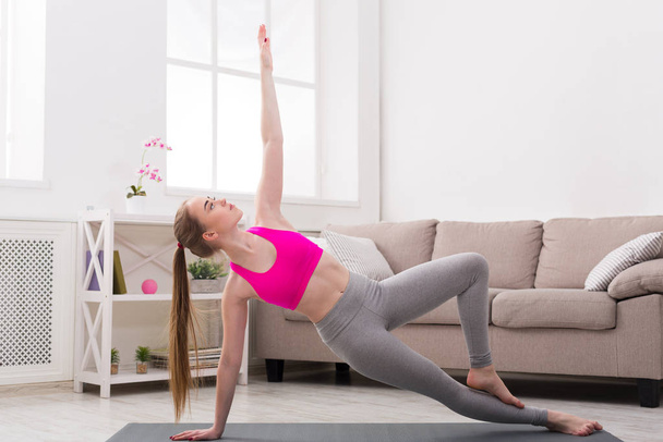 Vrouw opleiding yoga in zijkant plank pose. - Foto, afbeelding