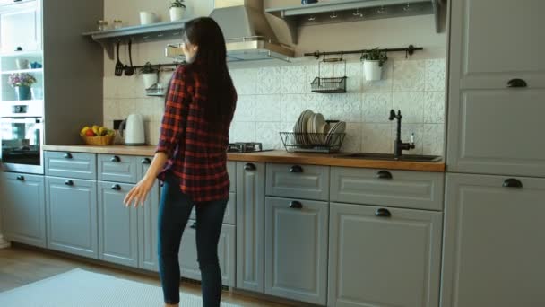 Portrait of young attractive woman dancing in her modern kitchen. Woman walking and dancing. - Video, Çekim