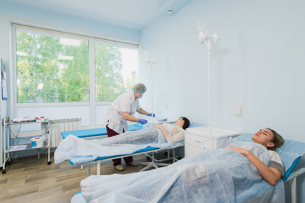 Медсестра подключает внутривенную капельницу в больничной палате
. - Фото, изображение