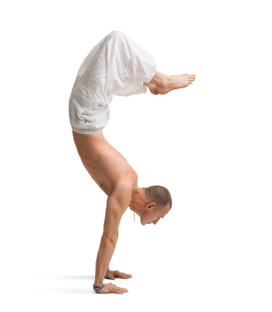Mature shirtless muscular man doing yoga handstand - Foto, Bild