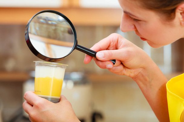Woman inspecting food with magnifying glass. - Foto, afbeelding
