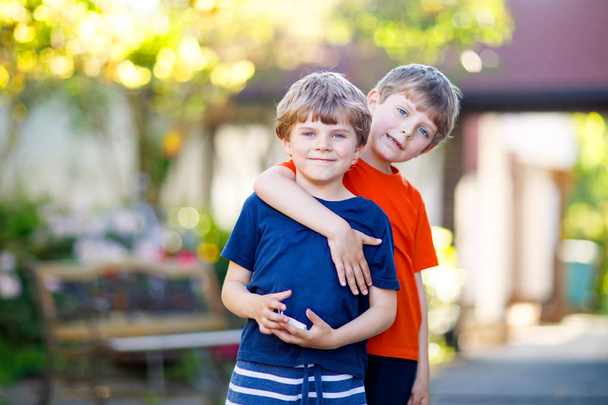 2 つの小さなアクティブな学校子供男の子、双子や兄弟の夏の日のハグ - 写真・画像