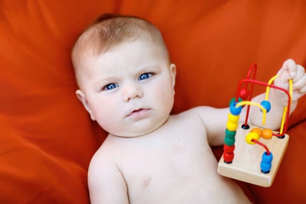 entzückendes neugeborenes Baby spielt mit buntem hölzernem Rasselspielzeug - Foto, Bild