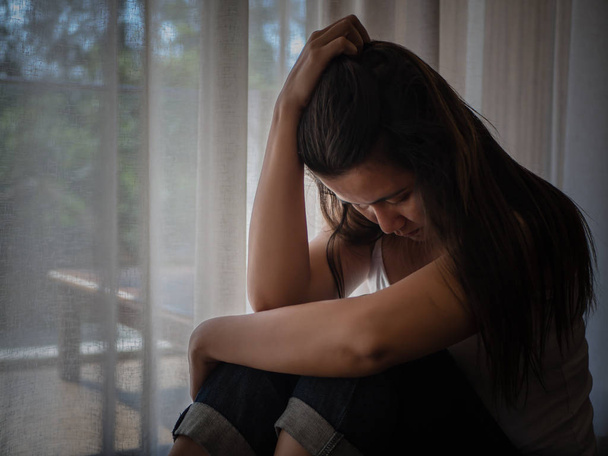 Zbliżenie depresji kobieta płacze sam siedząc na drewnianej podłodze. Smutna kobieta koncepcja. - Zdjęcie, obraz