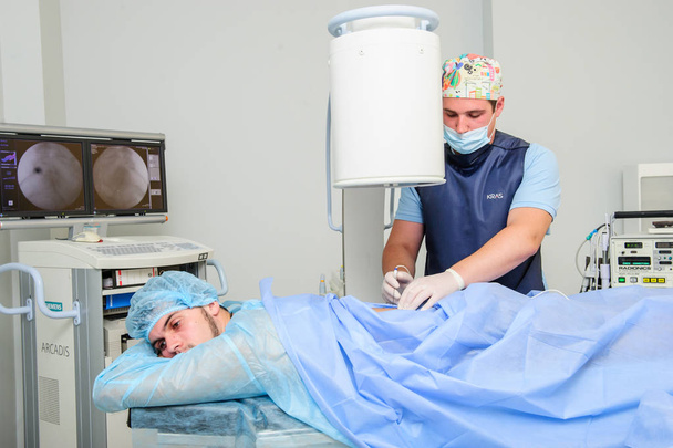Equipo de cirujanos ortopédicos en la sala de emergencias en uniforme estéril realizando cirugía en la columna vertebral humana, en el cemte de la columna vertebral
 - Foto, Imagen