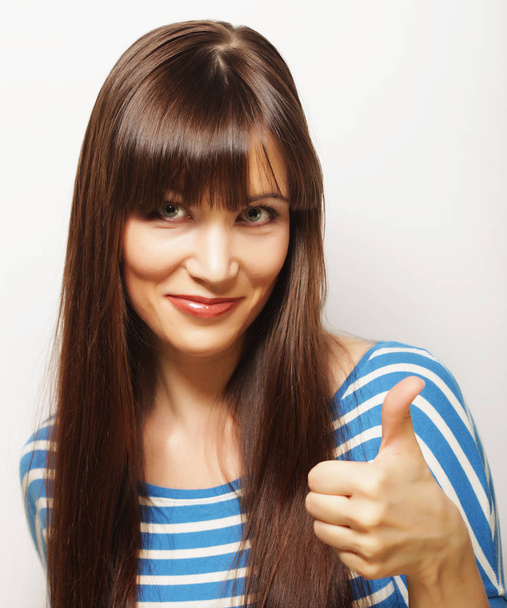 Happy smiling beautiful young woman showing thumbs up gesture - Foto, afbeelding