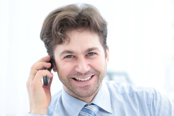Pewni biznesmen rozmawia przez telefon i uśmiecha się do kamery - Zdjęcie, obraz