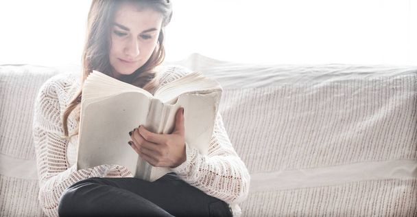 Tyttö lukee kirjaa sohvalla
 - Valokuva, kuva