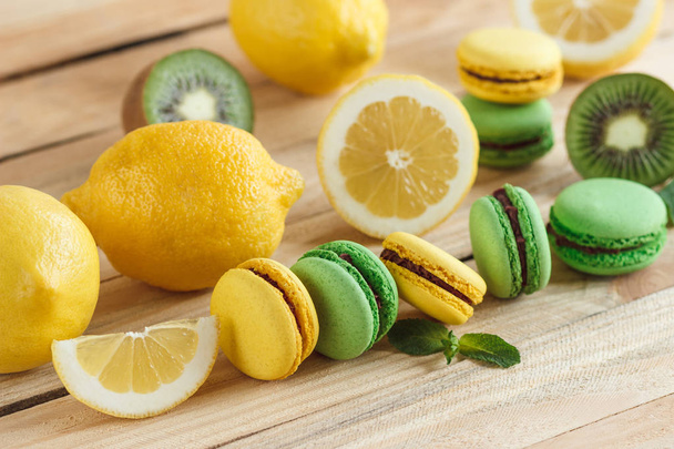 Green and yellow french macarons with kiwi, lemon and mint decorations - Zdjęcie, obraz