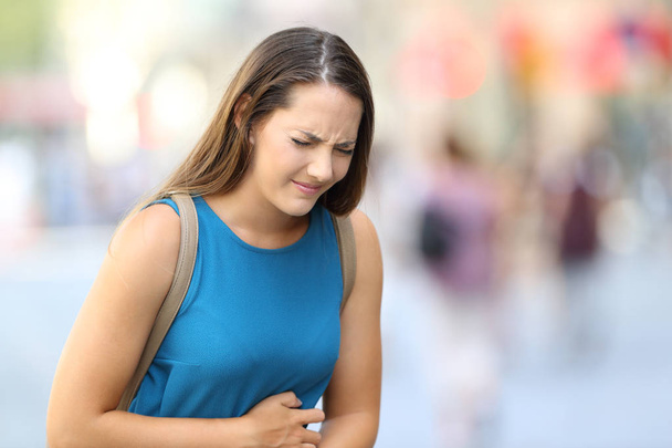 Woman suffering belly ache outdoor in the street - Foto, imagen