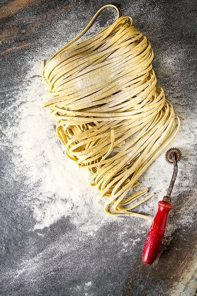 Homemade italian tagliatelle with flour. Dark background. - Фото, зображення